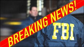The image shows shows two people in blue nylon jackets. One has their back to the camera and the words “FBI” in yellow can be seen across the shoulders. A red and yellow banner runs diagonally from corner to corner. It states “Breaking news.”