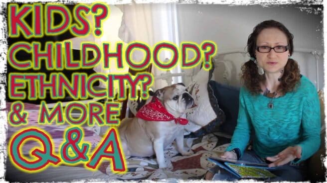 Emily Moran Barwick of Bite Size Vegan is shown sat on a bed. An open Ipad is on her lap and her beloved Ooby is at her side. She is looking at the camera. Overlaying the image are the words “Kids? Childhood? Ethnicity? And more. Q and A”