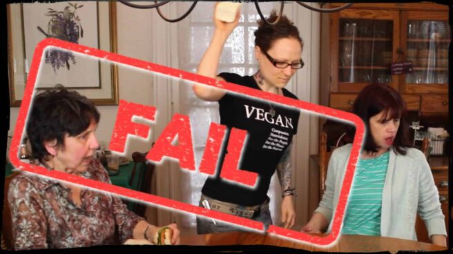 Around a dining table two people are seated with looks of alarm upon their faces. Emily Moran Barwick of Bite Size Vegan is seen in the process of throwing a large block of tofu onto the middle of the table. Overlaying the image, as if stamped upon it, is the word “Fail”.