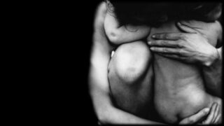 The monotone image is a close up of a mother as she envelops a young child in her arms.