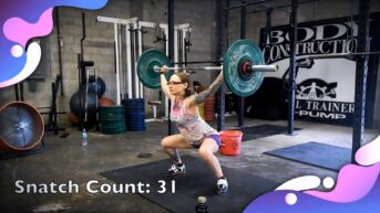 Emily Moran Barwick of Bite Size Vegan is shown lifting a weights in the snatch position.