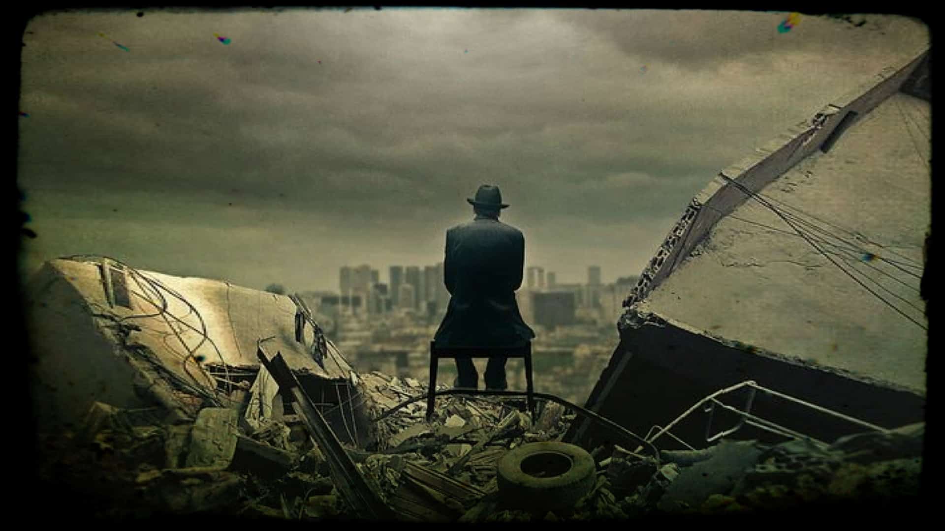 A seated figure, their back to the camera is shown under a dark and ominous sky. The figure looks toward a city skyline in the distance. They are surrounded by the rubble of a collapsed building and the discards of modern life.