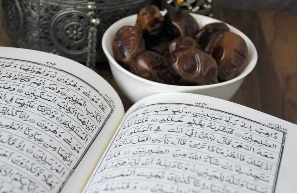 An open Quran, the scriptural source for halal dietary laws, next to a bowl of dates.