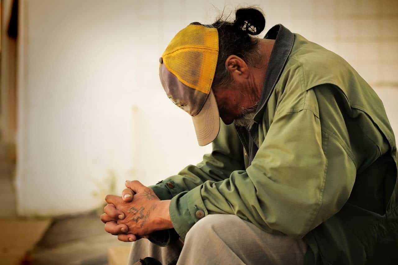 A slaughterhouse worker hunched over with his hands clasped, struggling with his mental health.