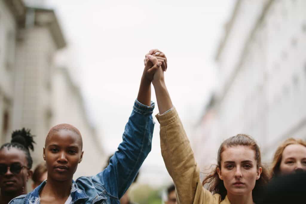 Two activists holding each other's hand, which are held above their heads in solidarity.