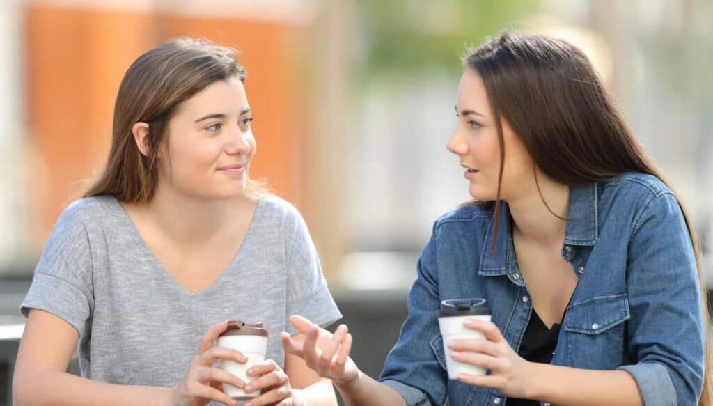 A woman listens attentively and with a welcoming expression as another woman shares something important.